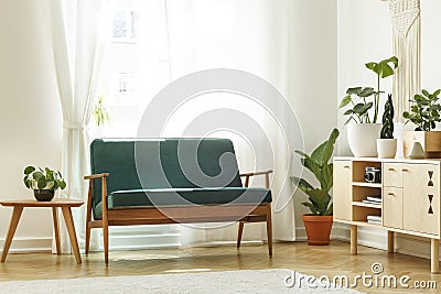 Real photo of a retro sofa next to a coffee table and cabinet wi Stock Photo