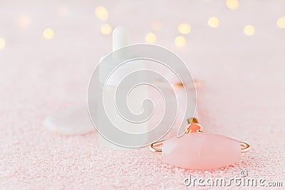 Real rose quartz facial roller, gua sha massage stone and face serum, selective focus Stock Photo