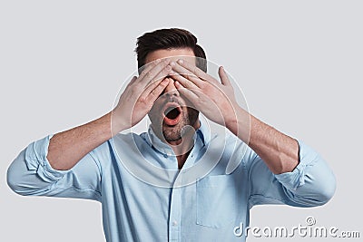 Real shock. Surprised young man covering eyes with hands while Stock Photo