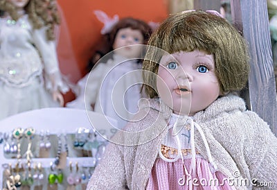 Realistic baby doll with blue eyes in a beige sweater and pink dress Stock Photo
