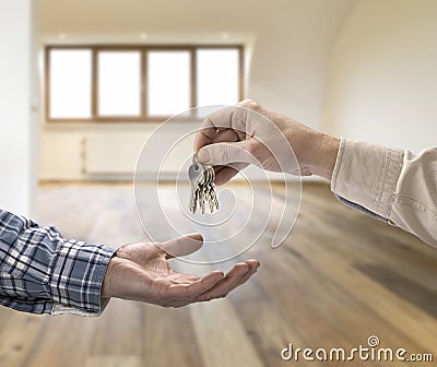 Realtor giving house key to buyer in loft room Stock Photo