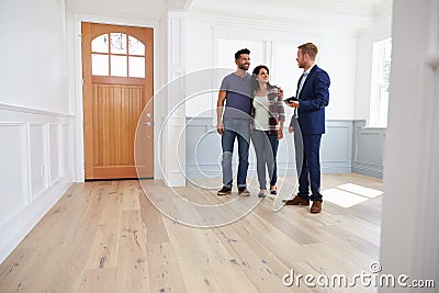 Realtor Showing Hispanic Couple Around New Home Stock Photo