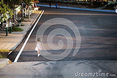 Rear back view of Asian kid girl jogging in park on summer or spring evening. Child play sports for good health. Children 5 years Stock Photo