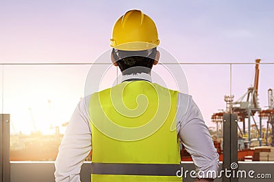 Rear view of an Asian construction worker with hardhat looking at the seaport Stock Photo