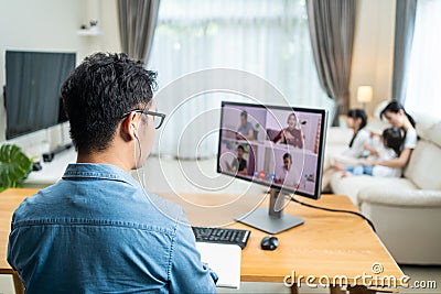 Rear view of Asian Working business man father talk to colleagues team on virtual video call conference online. Male freelance wor Stock Photo