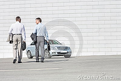 Rear view of businessmen carrying briefcases while walking towards car on street Stock Photo