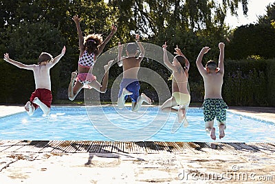 Rear View Of Children Jumping Into Outdoor Swimming Pool Stock Photo