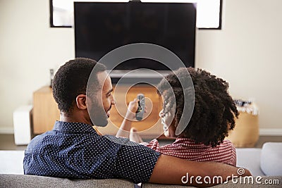 Rear View Of Couple Sitting On Sofa Watching TV Together Stock Photo