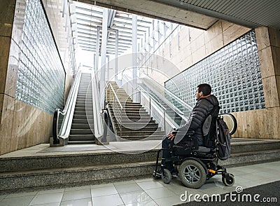 Rear View Of A Disabled Man On Wheelchair In Front Of escalator and staircase with copy space Stock Photo