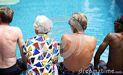 Rear view of diverse senior adults sitting by the pool enjoying summer together Stock Photo