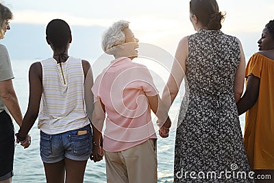 Rear view of diverse senior women holding hands together at the Stock Photo