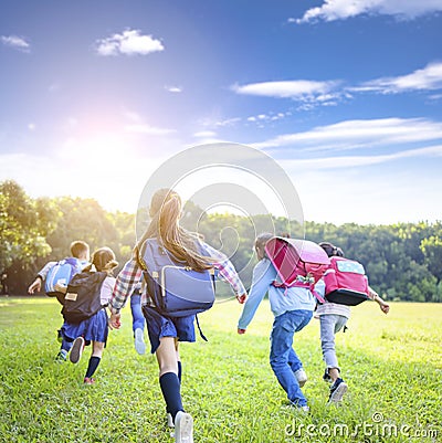 Rear view of elementary school kids running on the grass Stock Photo