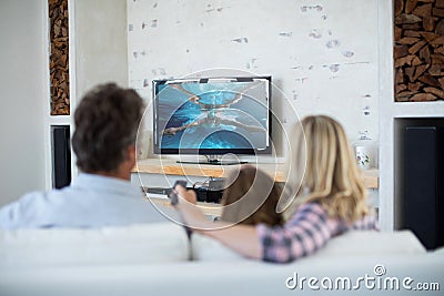 Rear view of family sitting at home together watching swimming competition on tv Stock Photo