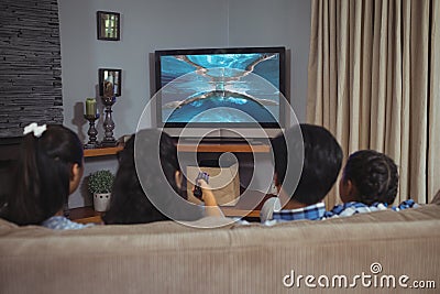 Rear view of family sitting at home together watching swimming competition on tv Stock Photo