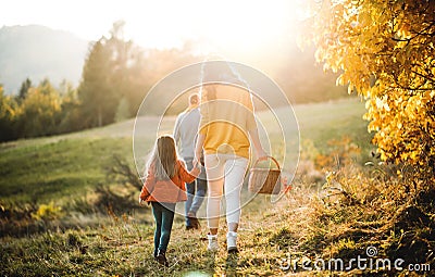 A rear view of family with small child on a walk in autumn nature. Stock Photo