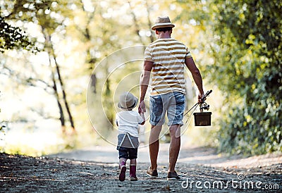 A rear view of father with a small toddler son going fishing. Stock Photo