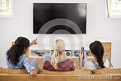 Rear View Of Female Friends Sitting On Sofa Watching Television Stock Photo