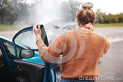 Rear View Of Female Motorist With Head Injury Getting Out Of Car After Crash Stock Photo