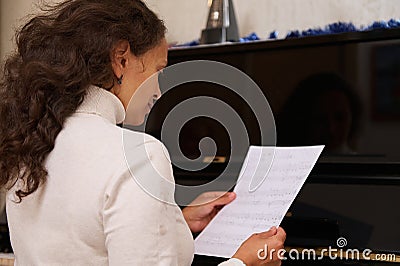 Rear view of a female pianist, musician, composer creating and composing music, playing piano forte indoor Stock Photo