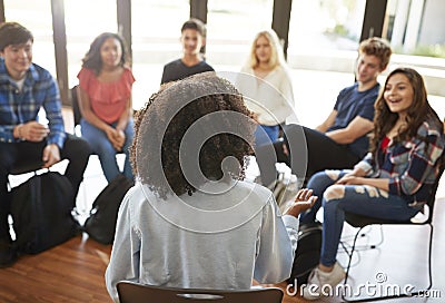 Rear View Of Female Tutor Leading Discussion Group Amongst High School Pupils Stock Photo