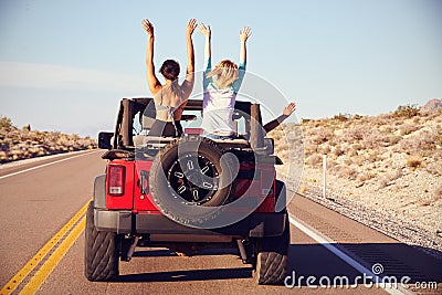 Rear View Of Friends On Road Trip Driving In Convertible Car Stock Photo