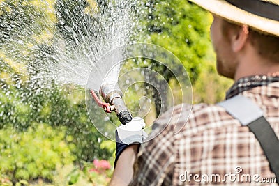 Rear view of gardener watering plants at garden Stock Photo