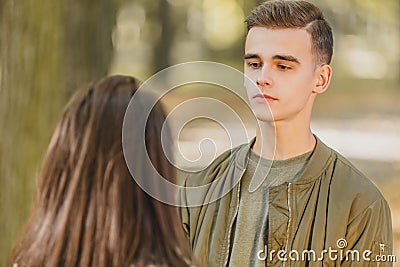 Rear view of a girl and boy looking at her with worried and unhappy facial exoression, while they are walking in city Stock Photo