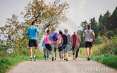 Rear view of group of multi generation people running a race competition in nature. Stock Photo