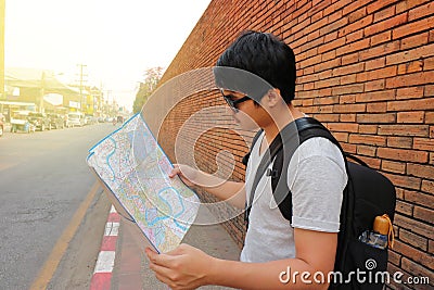 Rear view of handsome young Asian backpacker exploring the map for right direction at Chiang Mai , Thailand. Travel and tourism as Stock Photo