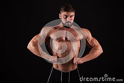 Rear view of healthy muscular young man with his arms stretched out isolated on black background Stock Photo