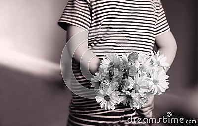 Rear view of kid with bunch of beautiful yellow Chrysanthemum behind his back in retro filter, Child in pajamas holds flowers behi Stock Photo