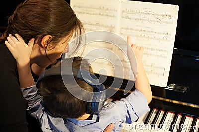 Rear view of a little boy learning piano from Stock Photo