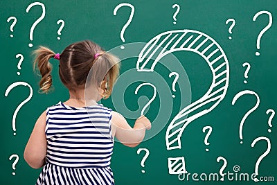 Little Girl Writing Question Marks On Chalkboard Stock Photo