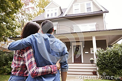 Rear View Of Loving Couple Looking At House Stock Photo