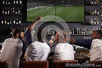 Rear View Of Male Friends Watching Game In Sports Bar Stock Photo