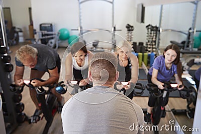 Rear View Of Male Trainer Taking Spin Class In Gym Stock Photo