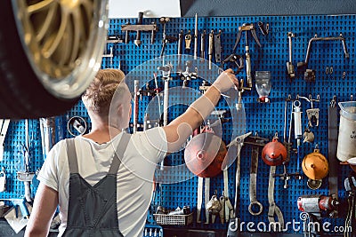 Rear view of a man choosing an useful tool during work in a repair shop Stock Photo