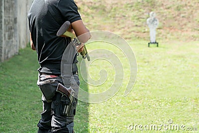 Rear view Man holding shotgun and carry handgun on the calf at front of Target in Shooting Range. Men Practicing Fire Pistol Stock Photo