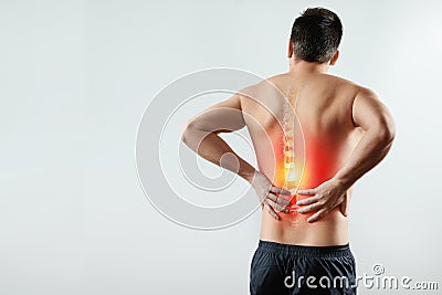 Rear view, the man holds his hands behind his back, pain in the back, pain in the spine, highlighted in red. Stock Photo