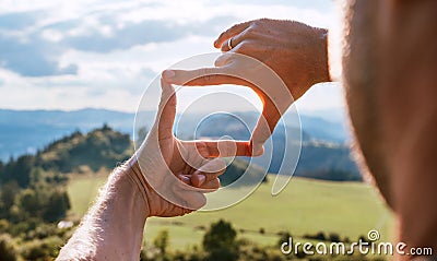Rear view of Man looking at mountain landscape framing with fingers, searching for best image composition as he hiking over the Stock Photo