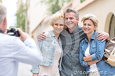 Rear view of man photographing male and female friends in city Editorial Stock Photo