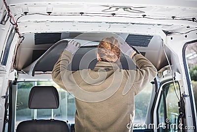 Man working on insulation inside his camper van Stock Photo