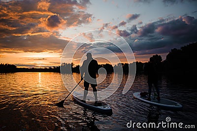 Rear view of man and woman on sup boards floating on river Stock Photo