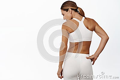 Rear view of middle aged sports woman back, masculine and fit body, standing in activewear against white background Stock Photo