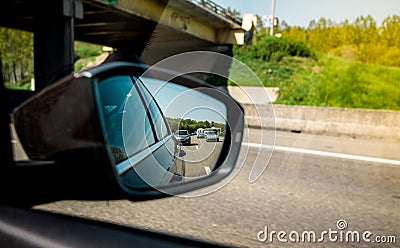 Rear view mirror of a car with multiple vehichles in the jam Stock Photo