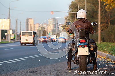 Rear view at motorcyclist with bike standing on urban road, female rider is ready to start movement in city Stock Photo