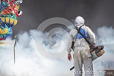 Outdoor healthcare worker using fogging machine spraying chemical to eliminate mosquitoes at Chinese shrine Stock Photo