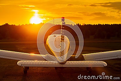 Rear view of a parked small plane on a sunset background. Silhouette of a private airplane landed at dusk. Stock Photo