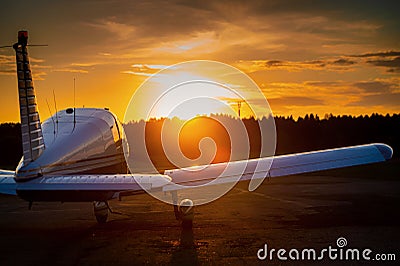 Rear view of a parked small plane on a sunset background. Silhouette of a private airplane landed at dusk. Stock Photo