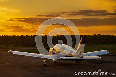 Rear view of a parked small plane on a sunset background. Silhouette of a private airplane landed at dusk. Stock Photo